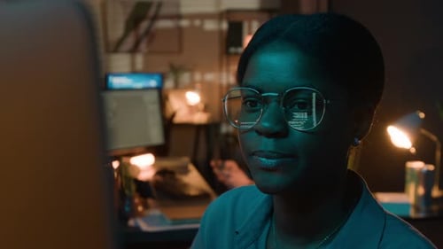 Black Female Software Engineer Coding with Screen Reflection in Glasses