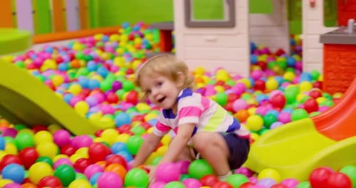 Enfant en bas âge glissant dans une salle de jeux colorée