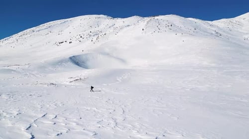 Aerial drone view of solo hiker walking in the mountains during the winter