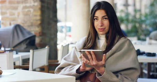 One morning a beautiful elegant woman eats breakfast at the outdoor cafe with a coffee and croissa