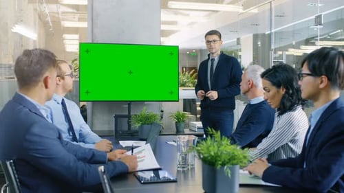 Young Gifted Businessman Gives Report/ Presentation to His Business Colleagues, Pointing at Green C