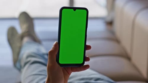 Person Holding Phone With Green Screen at Home