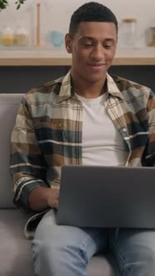 Glad Smiling African American Man Playing Video Game with Laptop Browsing Enjoying Working at Home