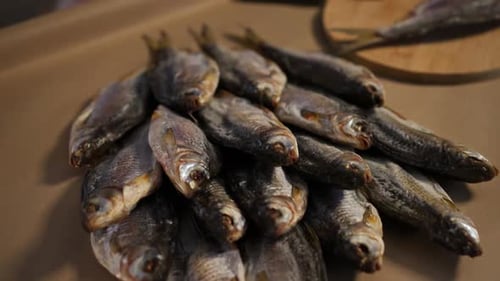 Primer plano de pescado seco sobre la mesa con la mano del macho colocando más sobre la pila
