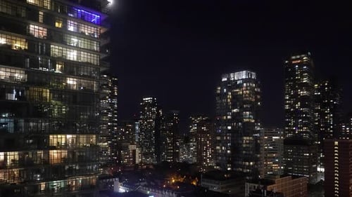 Time lapse shot of moon shining over modern buildings in downtown district