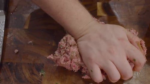 Close up on hands mashing meat on wooden cut board fro making meatballs. Cooking Rigatoni con polpe