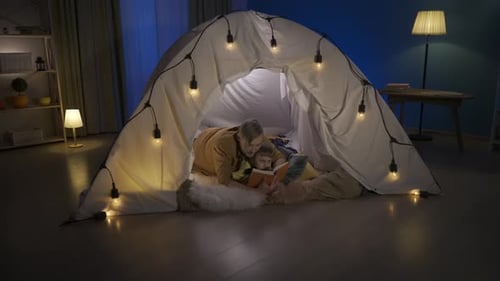 Adult and Child Reading Together in Cozy Tent