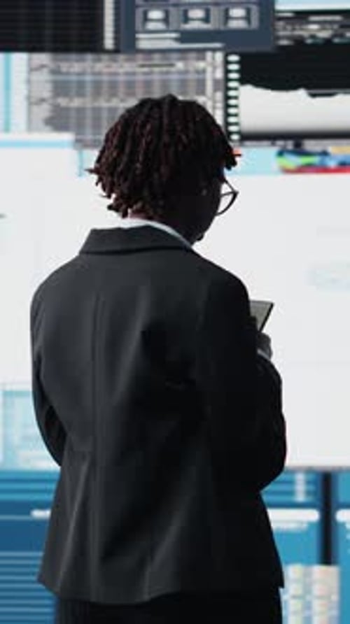 Woman Checks Phone in Front of Data Screens