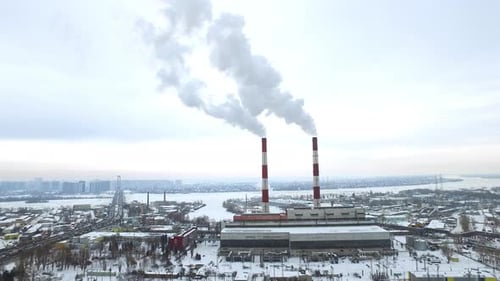 Aerial panorama of industrial chimneys smoking in winter city skyline
