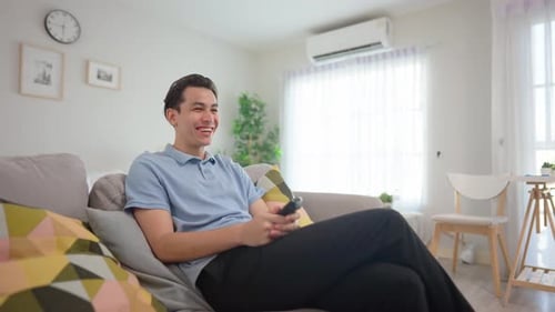 Man Relaxing on Couch Watching Television, Smiling