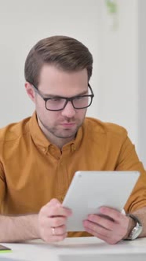 Adult Man Using Tablet Device Looking Upset Indoors