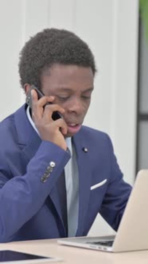 Young Man in Suit Talking on Phone at Desk