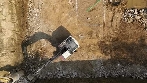 Excavator Moves Earth in Construction Site Aerial
