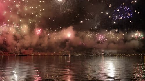 Colorful Fireworks Burst in Air Reflecting on Water Surface