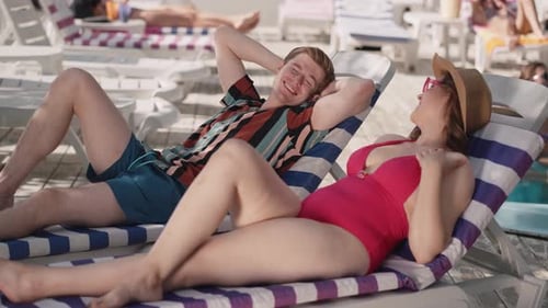 Couple Enjoying a Sunny Day at the Beach Relaxing on Loungers in the Summer Sun