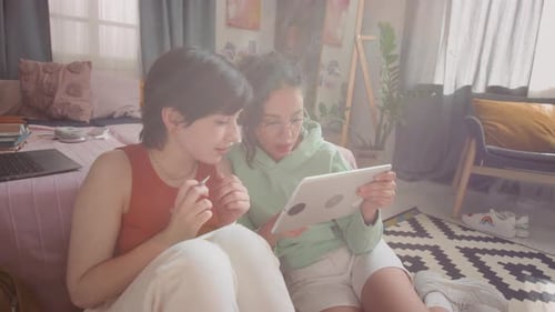 Two Friends Using Tablet Together Indoors
