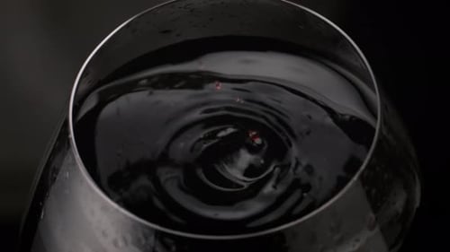 Wine dropping in glass of red wine