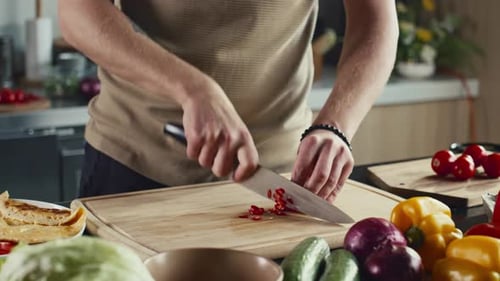 Young Adult Slices Vegetables in Bright Kitchen