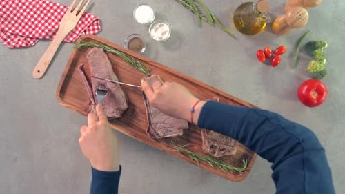 Top view static shot of female hands cutting steak over wooden dish