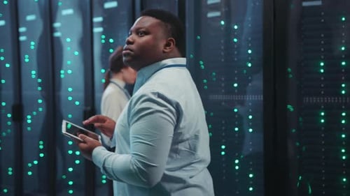 Server Room Technicians Working With Digital Tablet