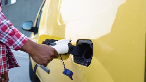 Unrecognizable Black Man Unplugs Charging Cable Electric Vehicle Green Energy Eco Friendly Fuel Male