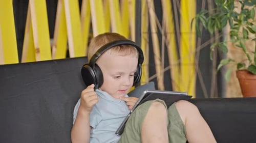 Child with Headphones Using Tablet on Couch