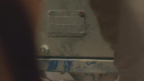 Hands Securing Plastic Bag to Dusty Metal Machine