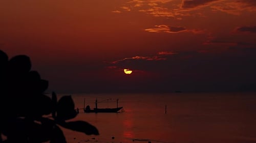 Fishing Boat Silhouette Floating On Calm Tropical Sea During Dramatic Red Sunset With Sun Behind