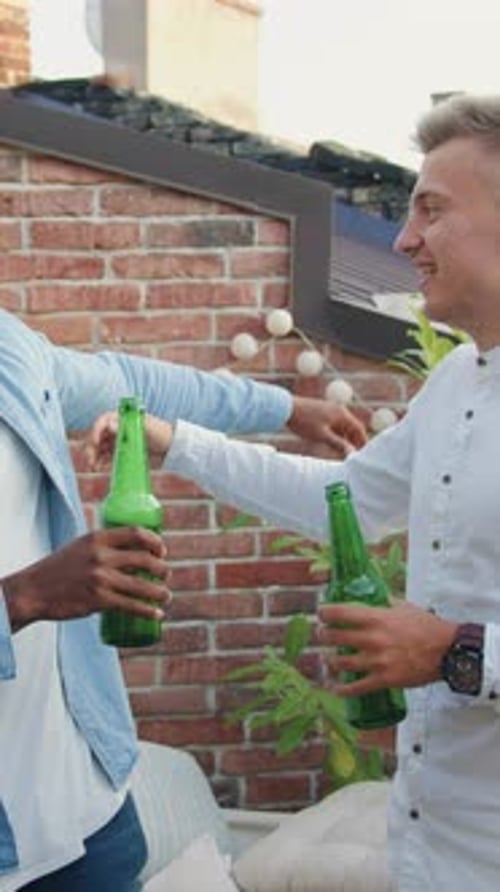 Friends Toasting with Green Bottles at Rooftop Party
