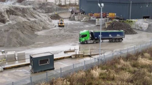 Truck parking waiting for excavator digger to load alongside British power station weigh station