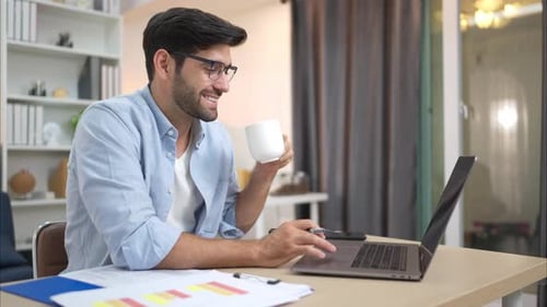 Adult Uses Laptop and Drinks Coffee at Home
