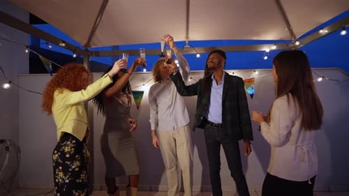 Friends Toasting and Celebrating at Rooftop Party at Night