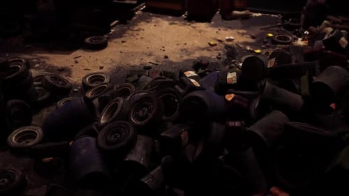 Black and Blue Tires Piled on a Dim Concrete Floor in a Cluttered Shop