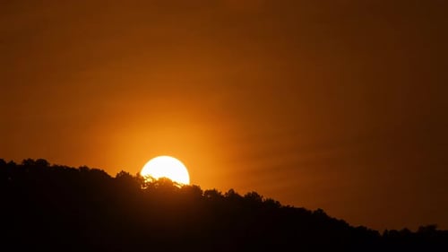Timelapse of dramatic sunrise with orange sky in a sunny day.