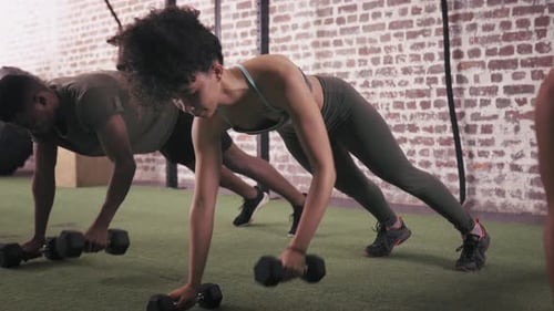 Push up, weightlifting with dumbbells, people and exercise for bodybuilding and sports group at gym