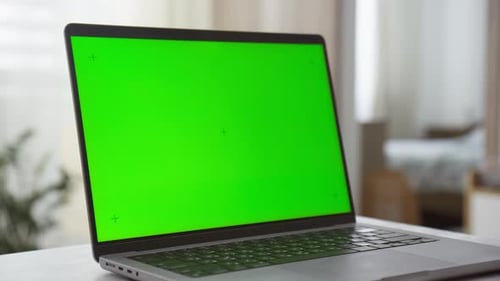 Laptop with Green Screen on Table in Bright Modern Interior