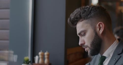 Slow Motion Tiltdown Portrait of Businessman Writing in Notebook and Using Laptop Computer in Cafe