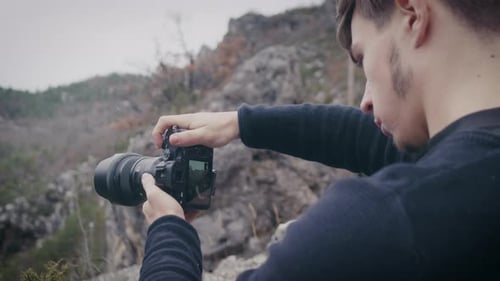 Portrait of photographer taking landscape photo using live view mode in camera