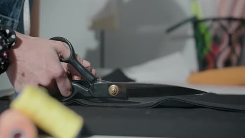 Seamstress Cutting Black Cloth in Studio
