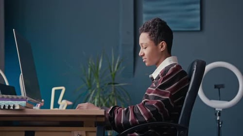 Teen works at computer in room with ring light