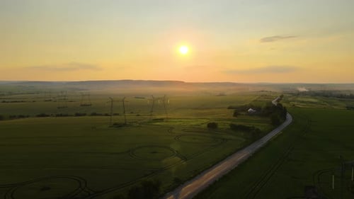 Dunkle Silhouette von Hochspannungstürmen mit Stromleitungen bei Sonnenaufgang