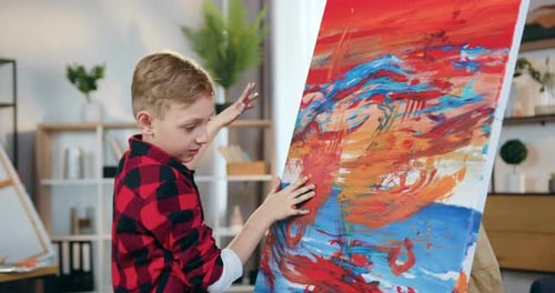 Close up of boy which drawing picture with hands in the paint applying the final touches on picture