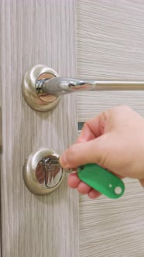 Hand Uses Key to Open Modern Interior Door