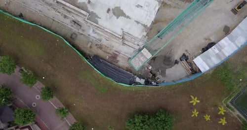 Vista aérea directamente sobre un edificio residencial en construcción, cerca de una colina y algunas casas de un