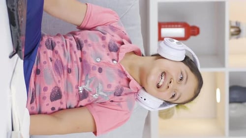 Smiling Child Listens to Music on Headphones with Laptop