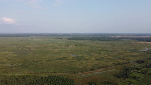 Aerial high view of rural landscape, green valley, roads, meadows, fields, trees and sky. Countrysid