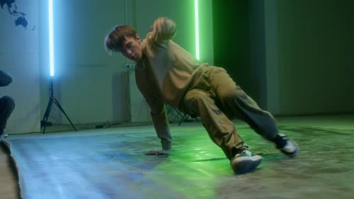 Young Adult Breakdancer Moves in Neon Lit Studio