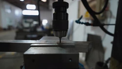 Nahaufnahme eines Bohrers, der in einer Werkstatt ein Loch in eine Metallstange bohrt