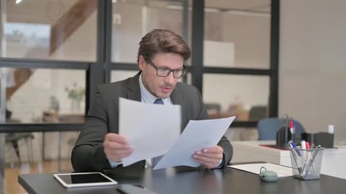 Middle Aged Businessman Working on Documents in Office