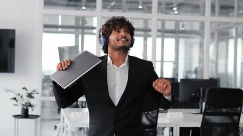 Funny Relaxed Indian Happy Businessman in Headphones Dancing in Office